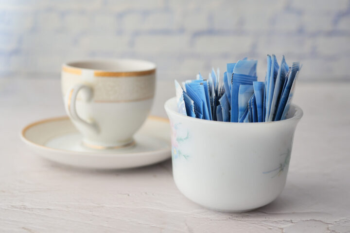 Sugar Substitute sweetener in a packet and cup of tea on table