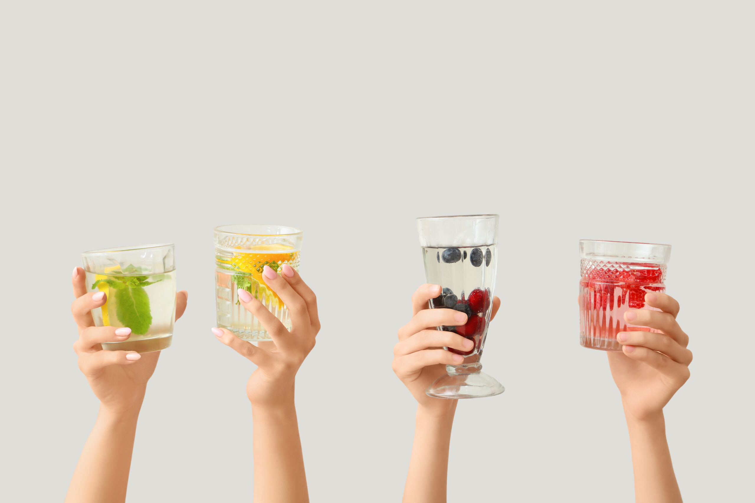 Many hands with infused water on light background