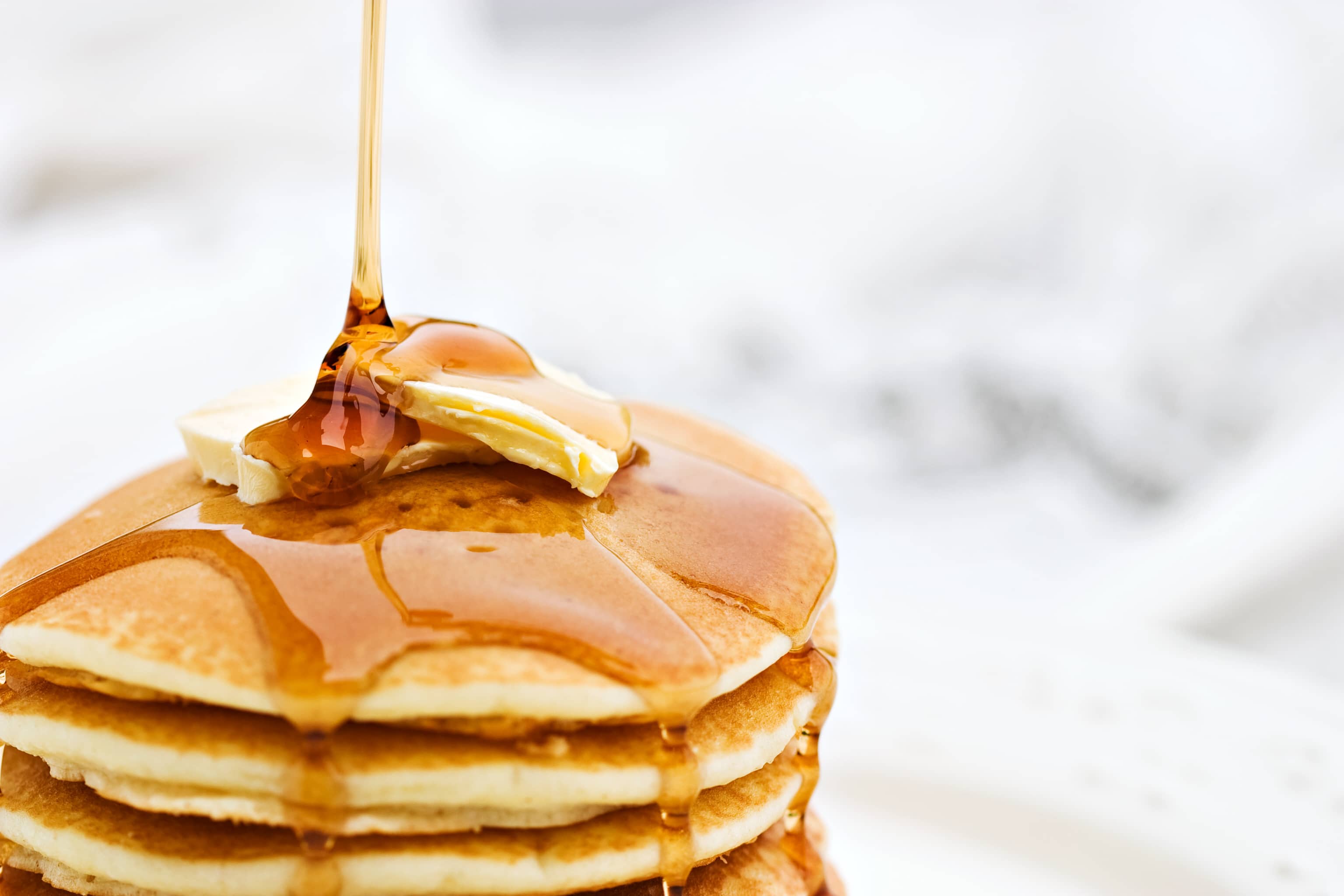 Maple syrup pouring onto pancakes. - Calorie Control Council