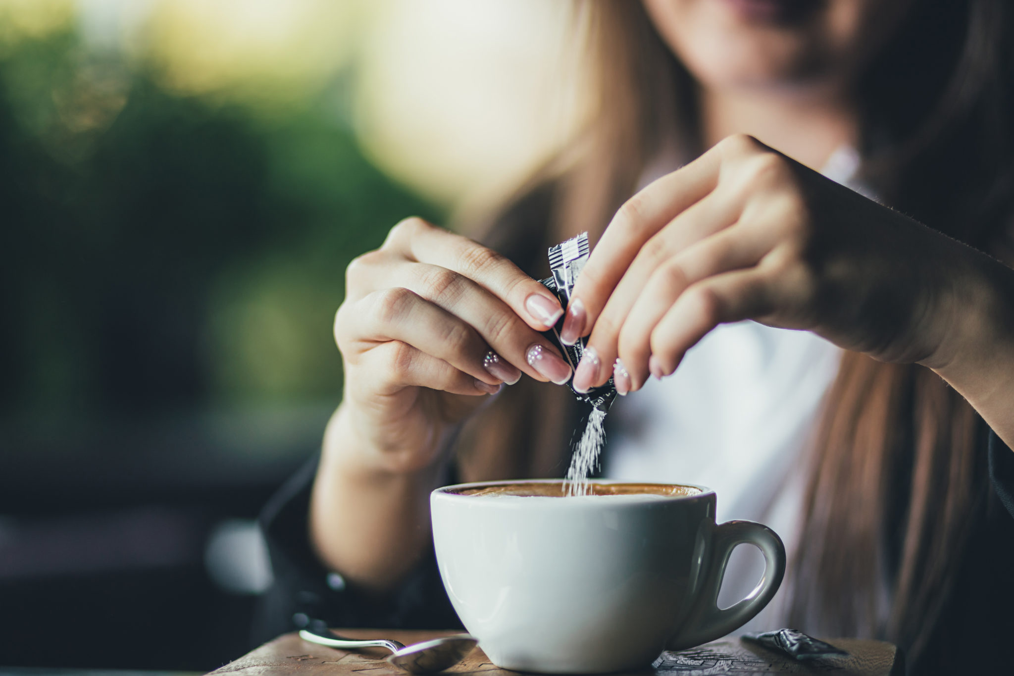 Woman putting sugar in coffee - Calorie Control Council